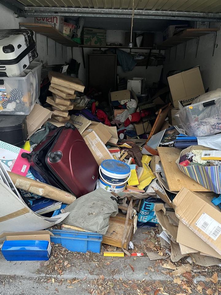 Garage rempli jusqu'au plafond de cartons, valises et planches, avant le débarras