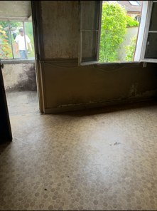 Pièce de la maison entièrement vidée, sol dégagé et fenêtres ouvertes, après le débarras