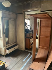Chambre de maison ancienne avec armoire à glace, commode et étagères en bois, avant le débarras